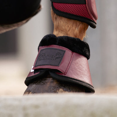 Person adjusting a horse's leg with protective boots in an outdoor setting