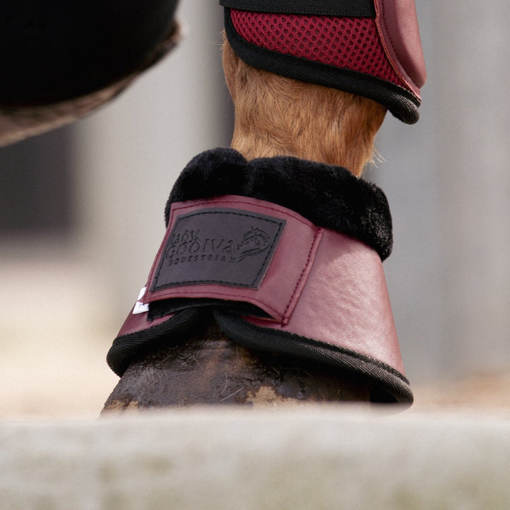 Person adjusting a horse's leg with protective boots in an outdoor setting