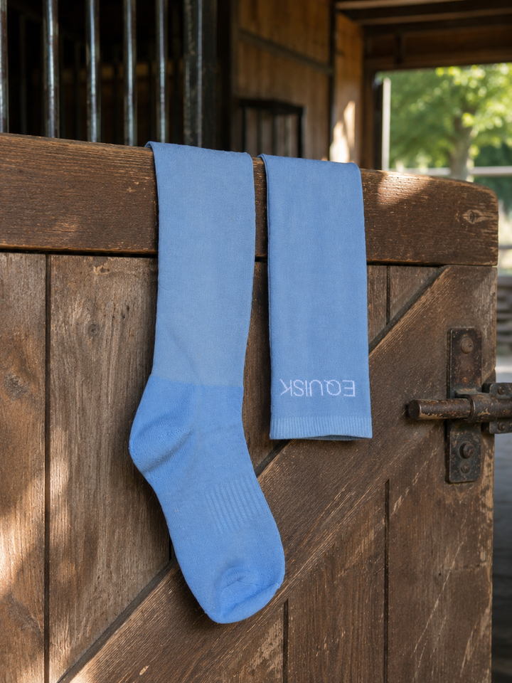 Two blue socks hanging on a wooden door with 'Equisk' branding.