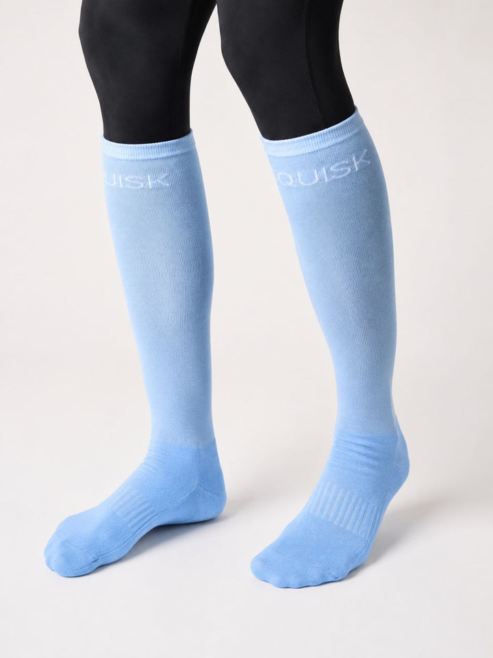 Light blue knee-high socks with 'EQUISK' branding worn by a person on a white background