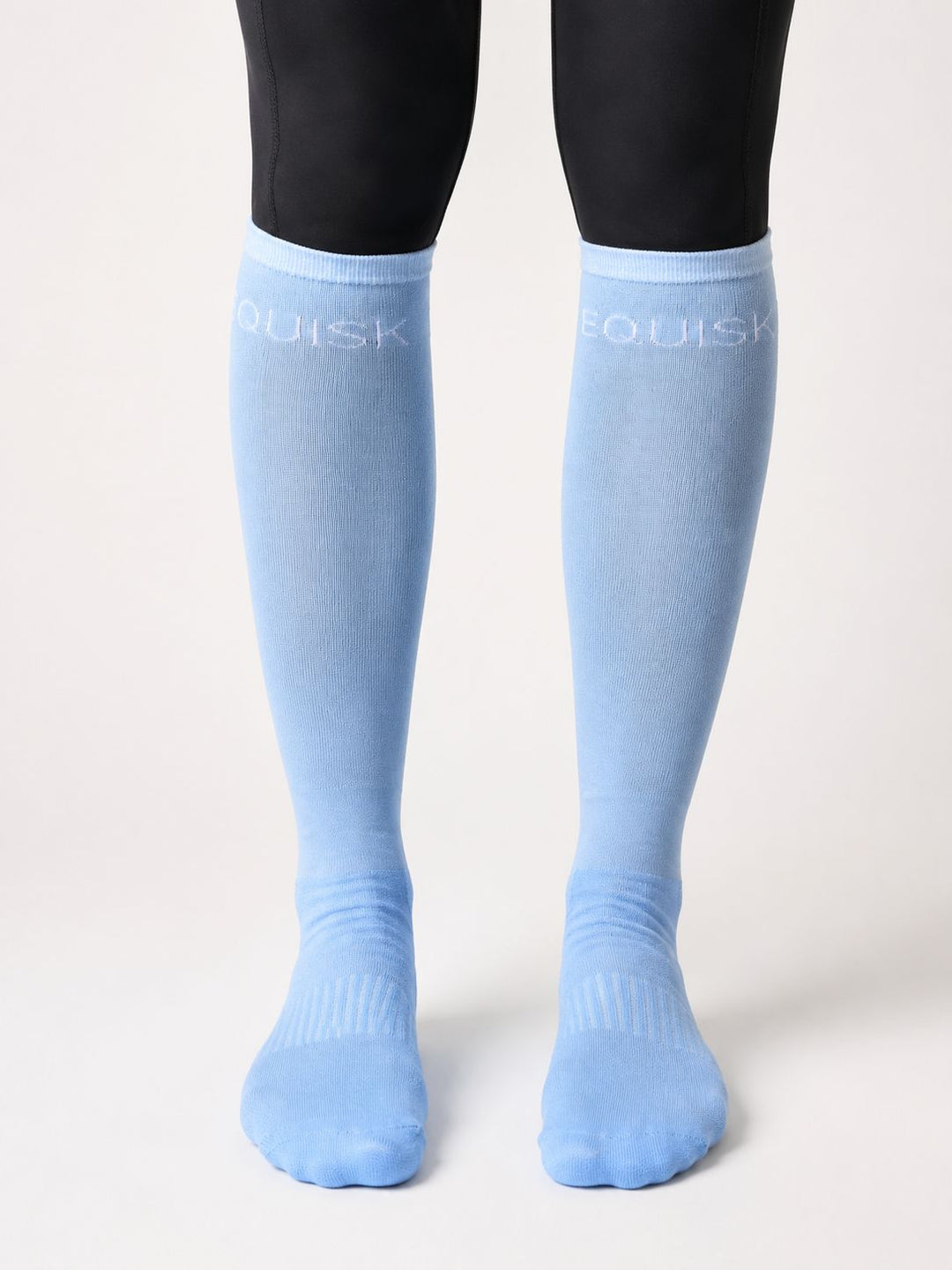 Light blue knee-high socks with 'EQUISK' branding worn by a person on a white background