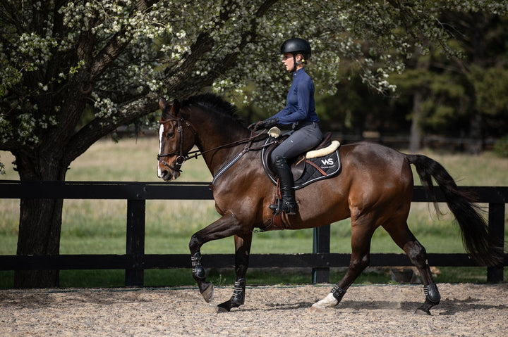 Model riding in Wilma Sport Slate Grey Hybrid Breeches – silicone knee grip breeches and Featherlight Training Shirt in Urban Navy.
